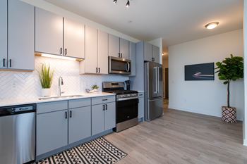a kitchen with gray cabinets and a black and white rug